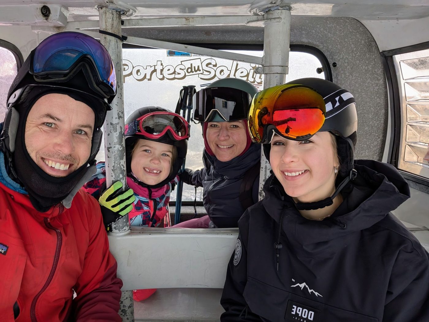 Our family of four smiling in ski helmets and goggles inside a Portes du Soleil gondola